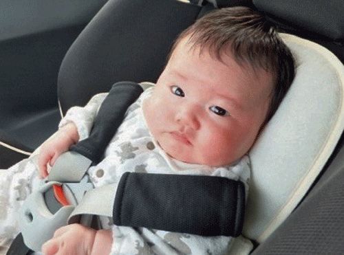 赤ちゃんがチャイルドシートに乗って少し不機嫌な画像